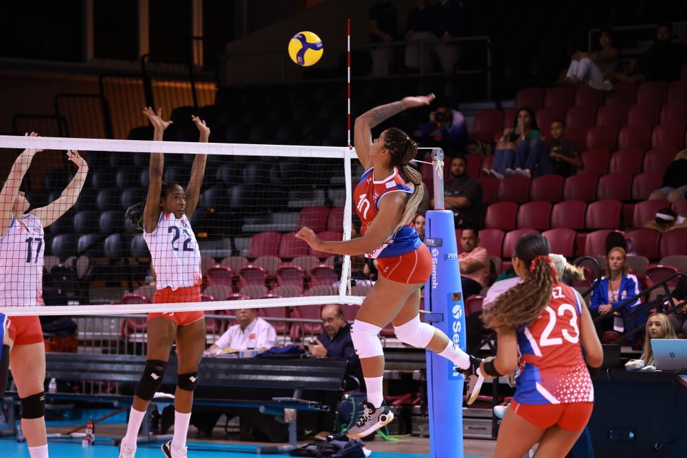 Women’s volleyball players competing at the net in match uniforms