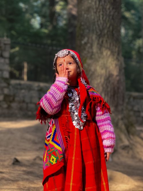 Free A young girl in colorful traditional clothing outdoors, surrounded by nature. Stock Photo