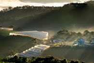 温室坐落在云雾缭绕的山间，黎明时分阳光明媚，景色宁静