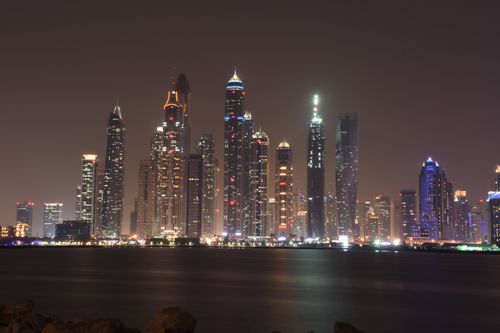 Free A captivating nighttime view of Dubai's illuminated skyline with reflection on the waterfront. Stock Photo