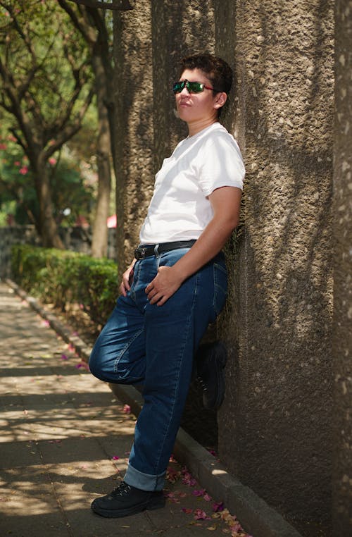 A man leaning against a tree with his hands in his pockets