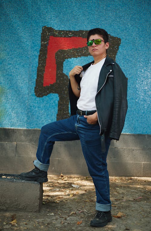 A man in jeans and a leather jacket posing for a photo