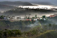 黎明时分，一辆红色的车辆行驶在云雾缭绕、松树掩映的山间蜿蜒道路上