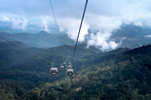 Stunning view of cable cars traversing a lush mountain landscape under a cloudy sky.
