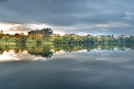 平静的湖泊倒映着周围的树木，上方是喜怒无常的灰色天空