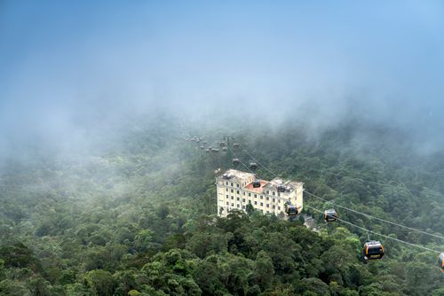 Free Aerial view of cable cars travelling over a misty mountain forest with a building. Stock Photo