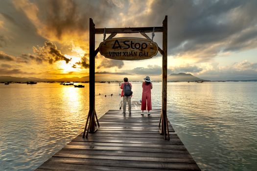 A couple enjoys a stunning sunset view from a pier at Vinh Xuân Đài.