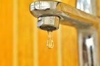 不锈钢水龙头上挂着一颗近距离拍摄的水滴，凸显了表面张力