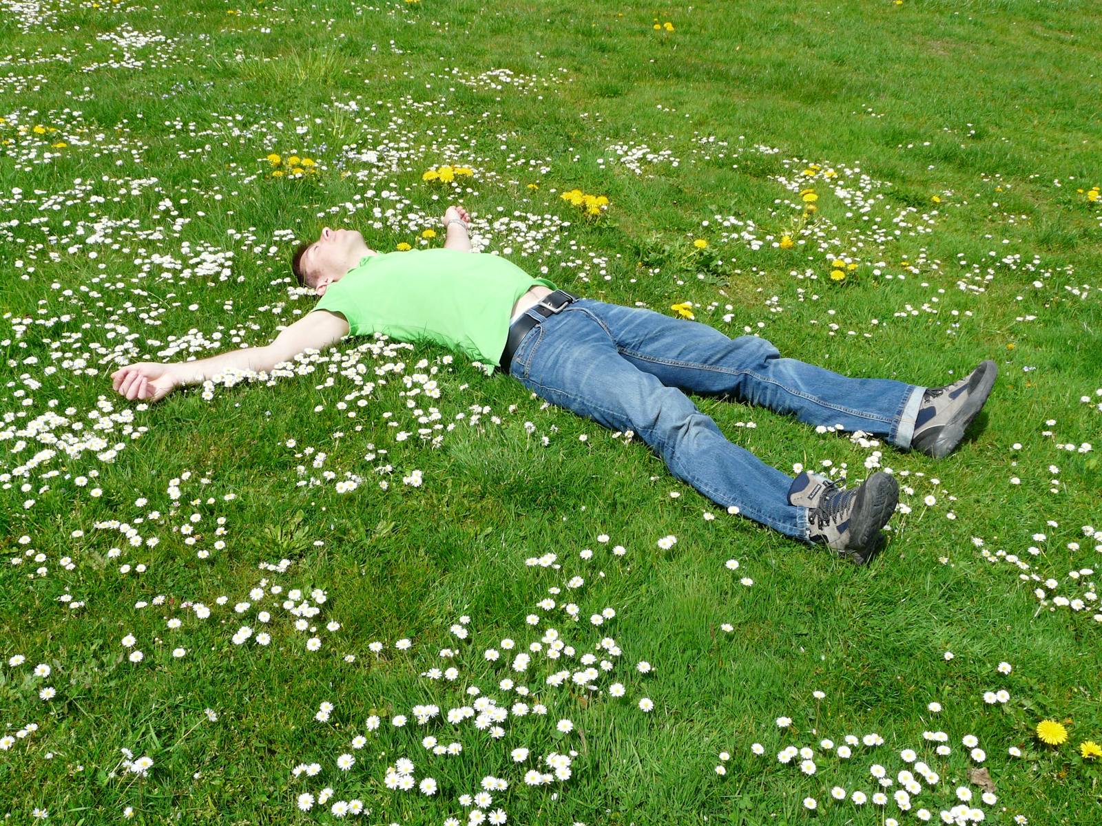 Man laying down in a patch of grass & flowers. 