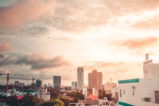 A city skyline during twilight featuring skyscrapers under a cloudy sky.