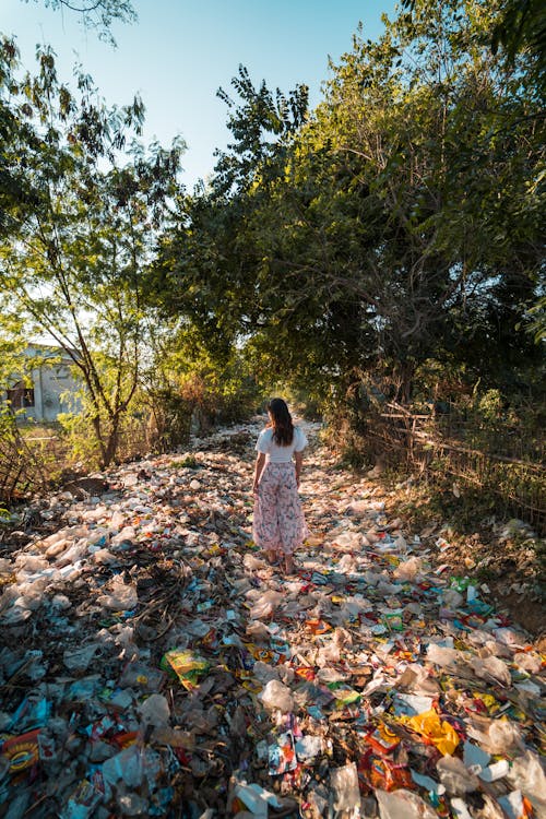 Foto De Uma Mulher Em Pé Sobre Uma Pilha De Lixo Perto De árvores