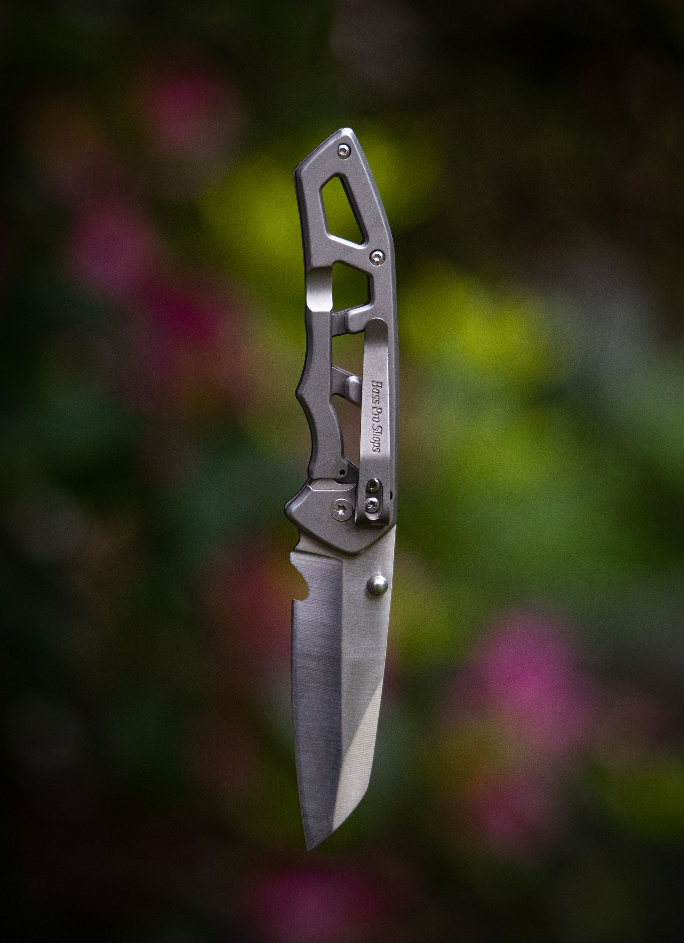 Close-up of a metallic Swiss army knife suspended against a blurred outdoor background