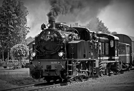 Black and white photo of a classic steam locomotive emitting smoke, evokes nostalgia for historical train travel.