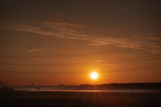 Beautiful sunset over a rural landscape with power lines and a clear sky enhancing nature's simplicity.