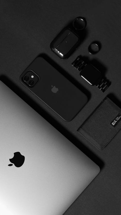Iphone, apple watch, and other accessories on a black background