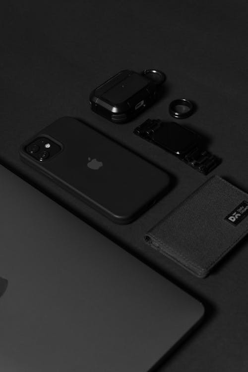 A black iphone, wallet, and other items on a table