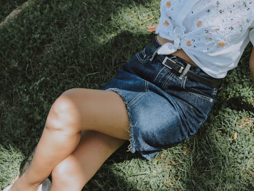 Woman in White Shirt and Blue Denim Skirt Sitting on Green Grass