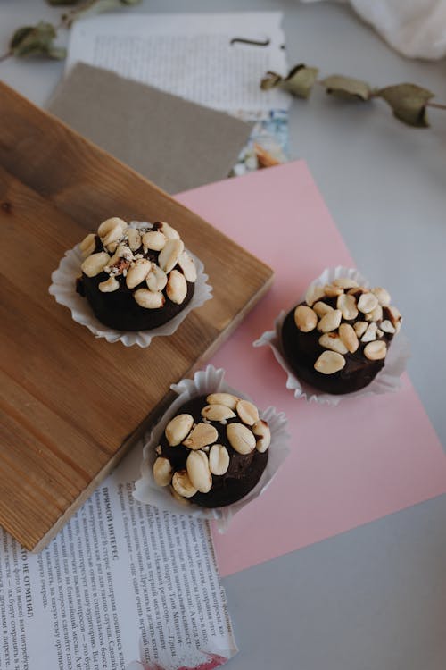 Three chocolate covered nuts on a wooden cutting board