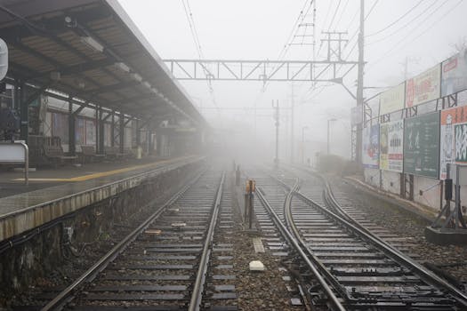 城市火车站雾气缭绕，铁轨和站台空无一人，营造出一种神秘的氛围