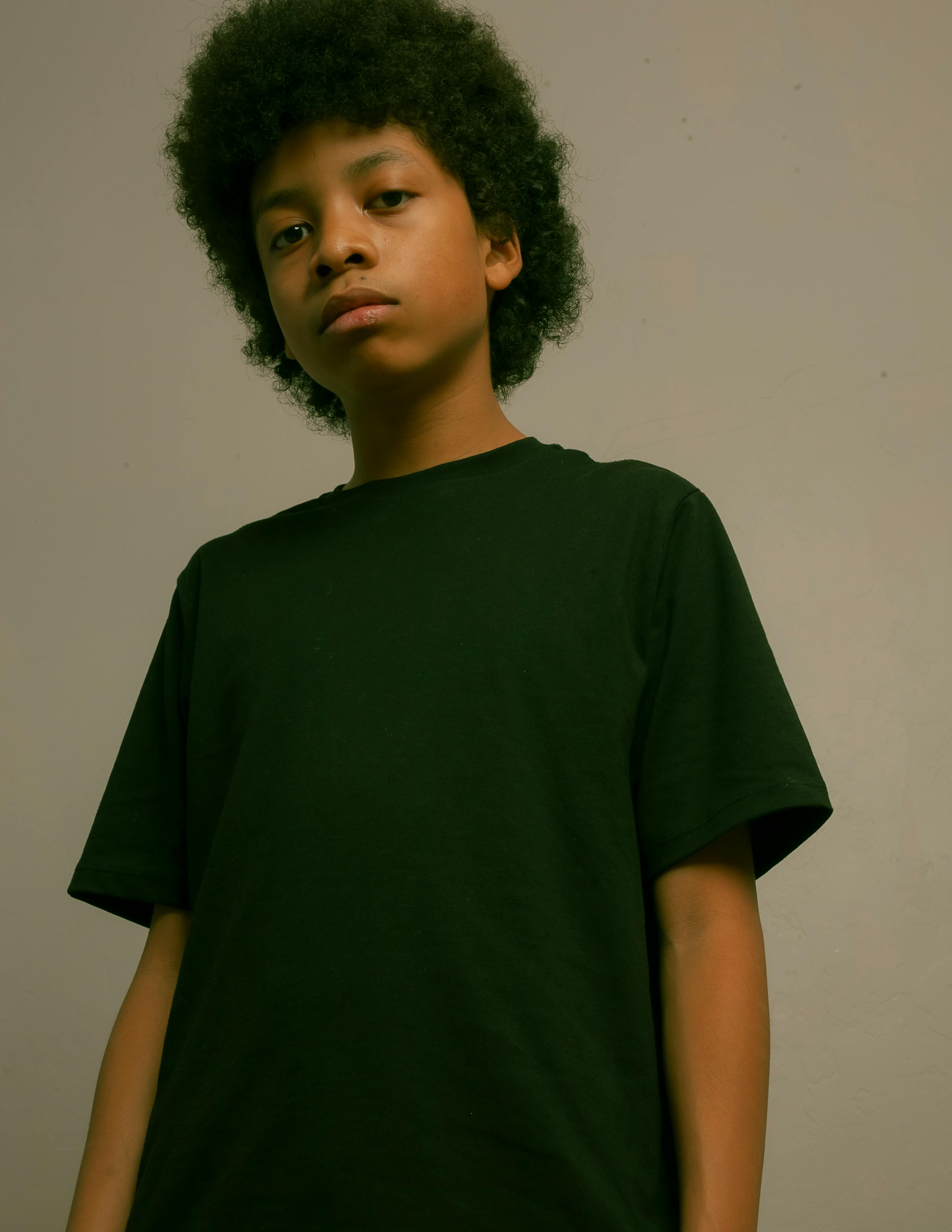 Fashion portrait of a young boy in a black t-shirt, studio setting.