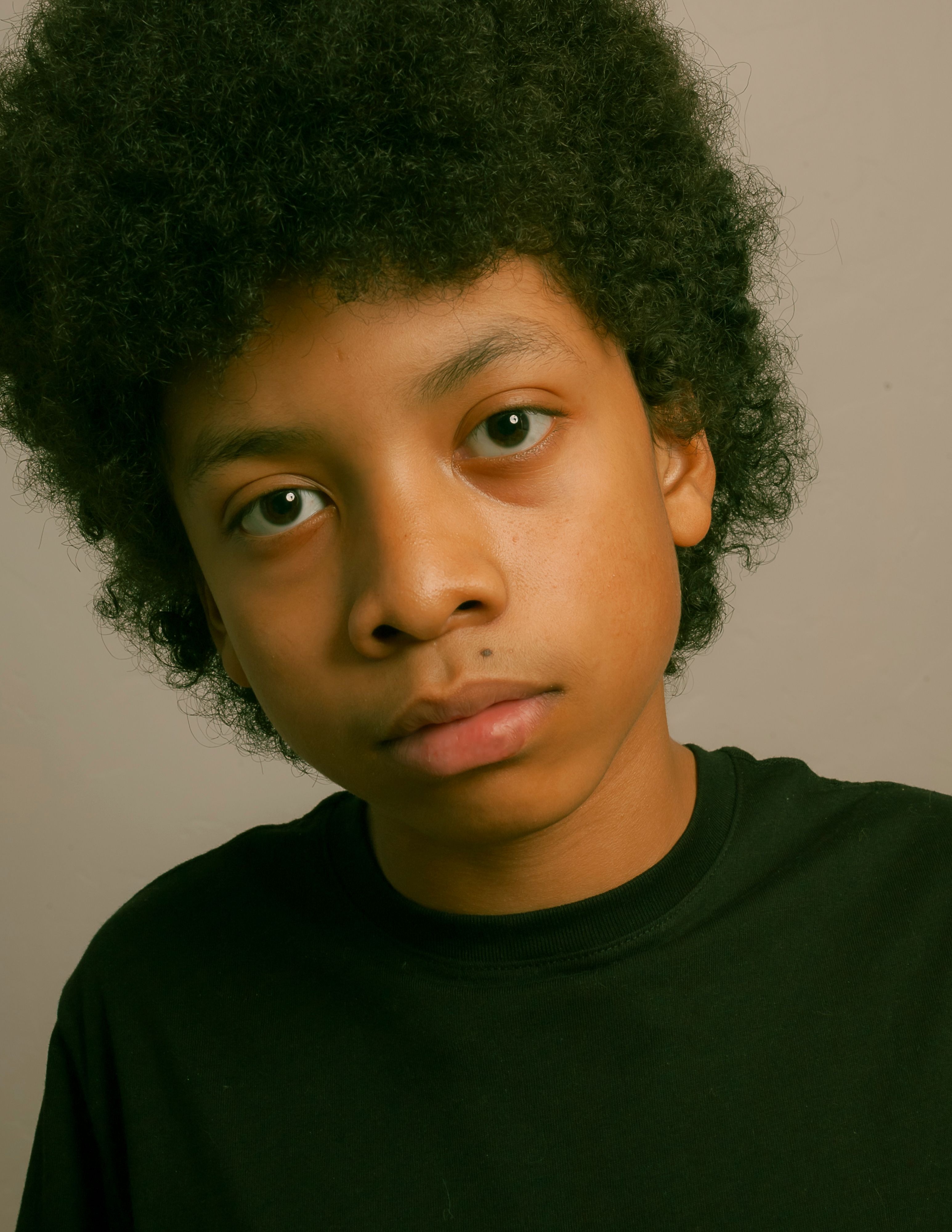 Close-up portrait of a young boy with afro hairstyle, studio setting in Los Angeles.