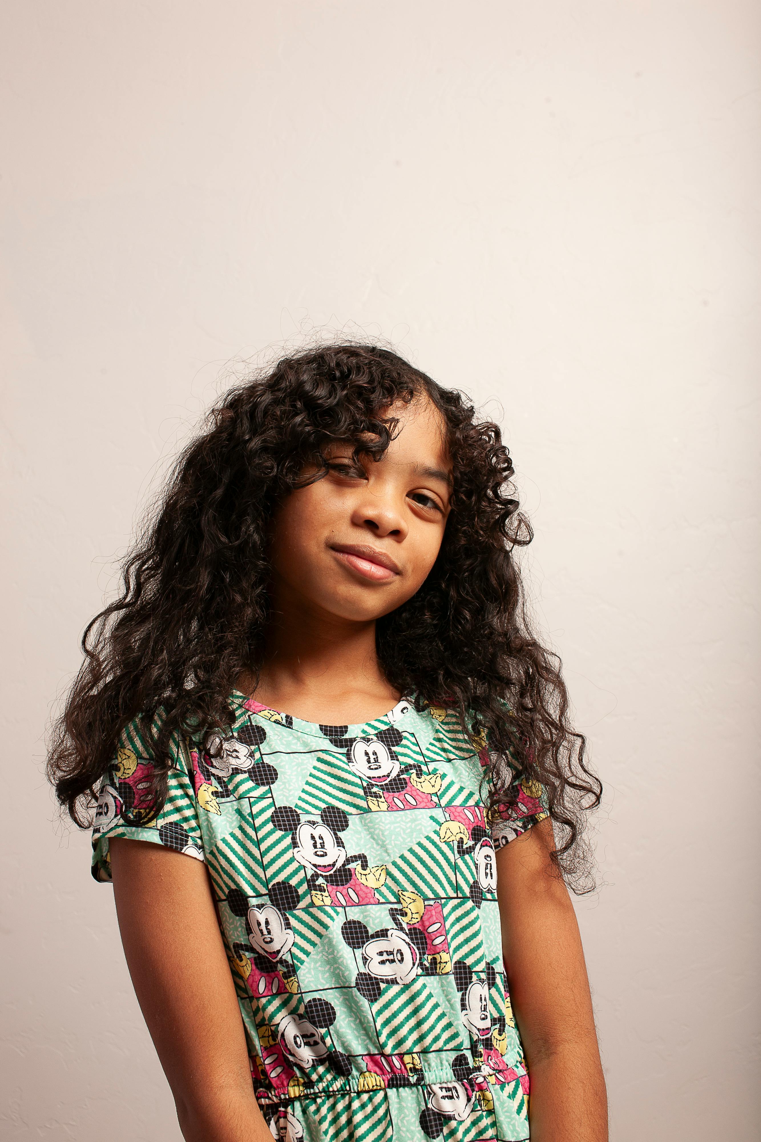 A young girl in a green dress with a mickey mouse print · Free Stock Photo