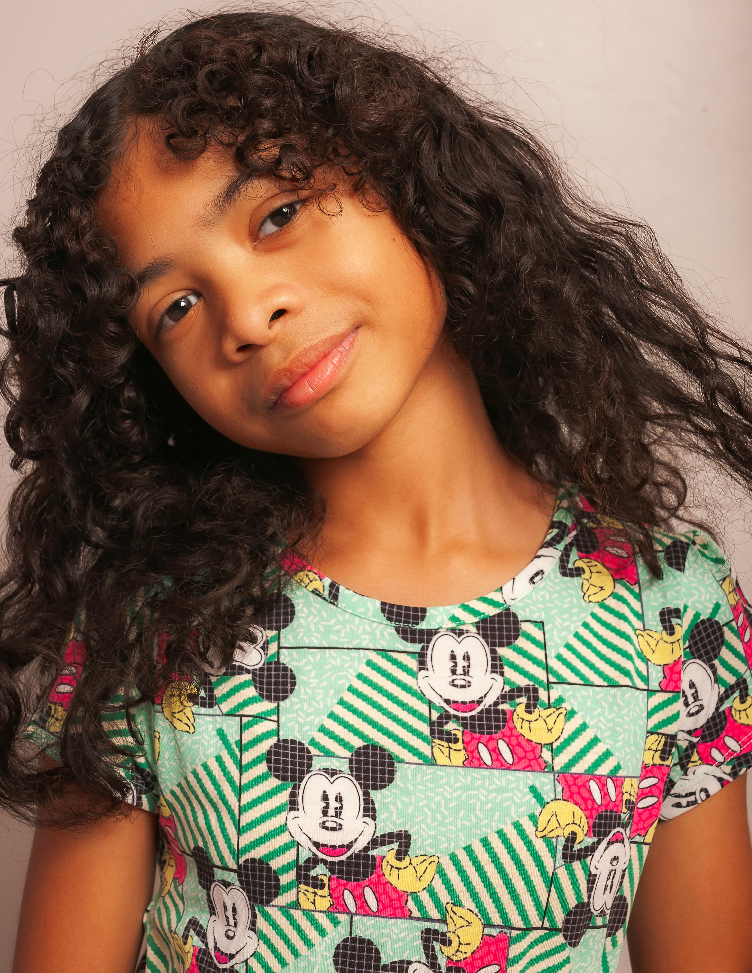 Adorable portrait of a young girl smiling warmly in a studio setting, radiating youthful joy.
