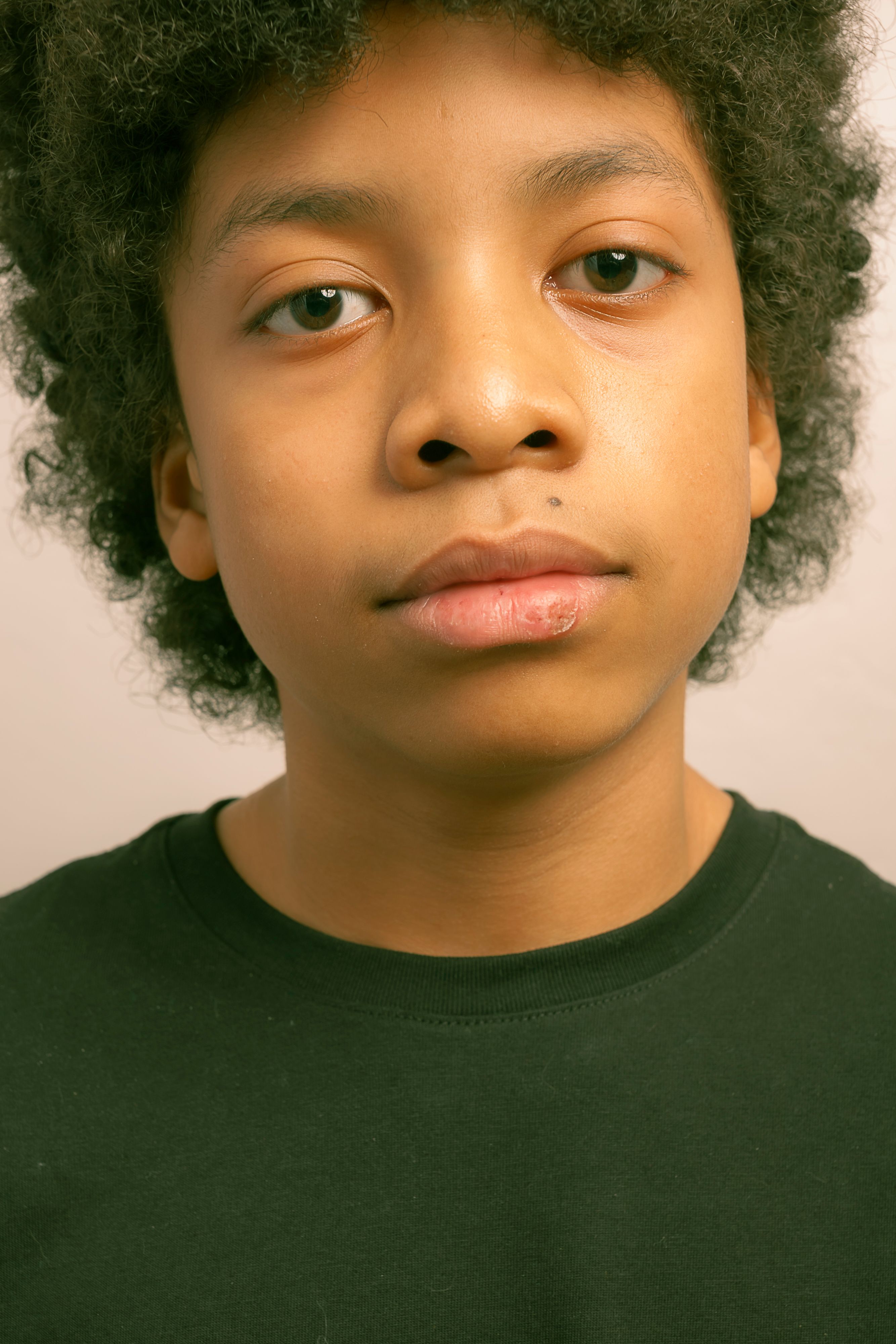 Close-up portrait of a black boy with curly hair in a studio.