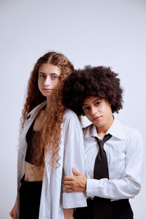 Free Two young women in stylish shirts and ties posing in a studio setting. Stock Photo