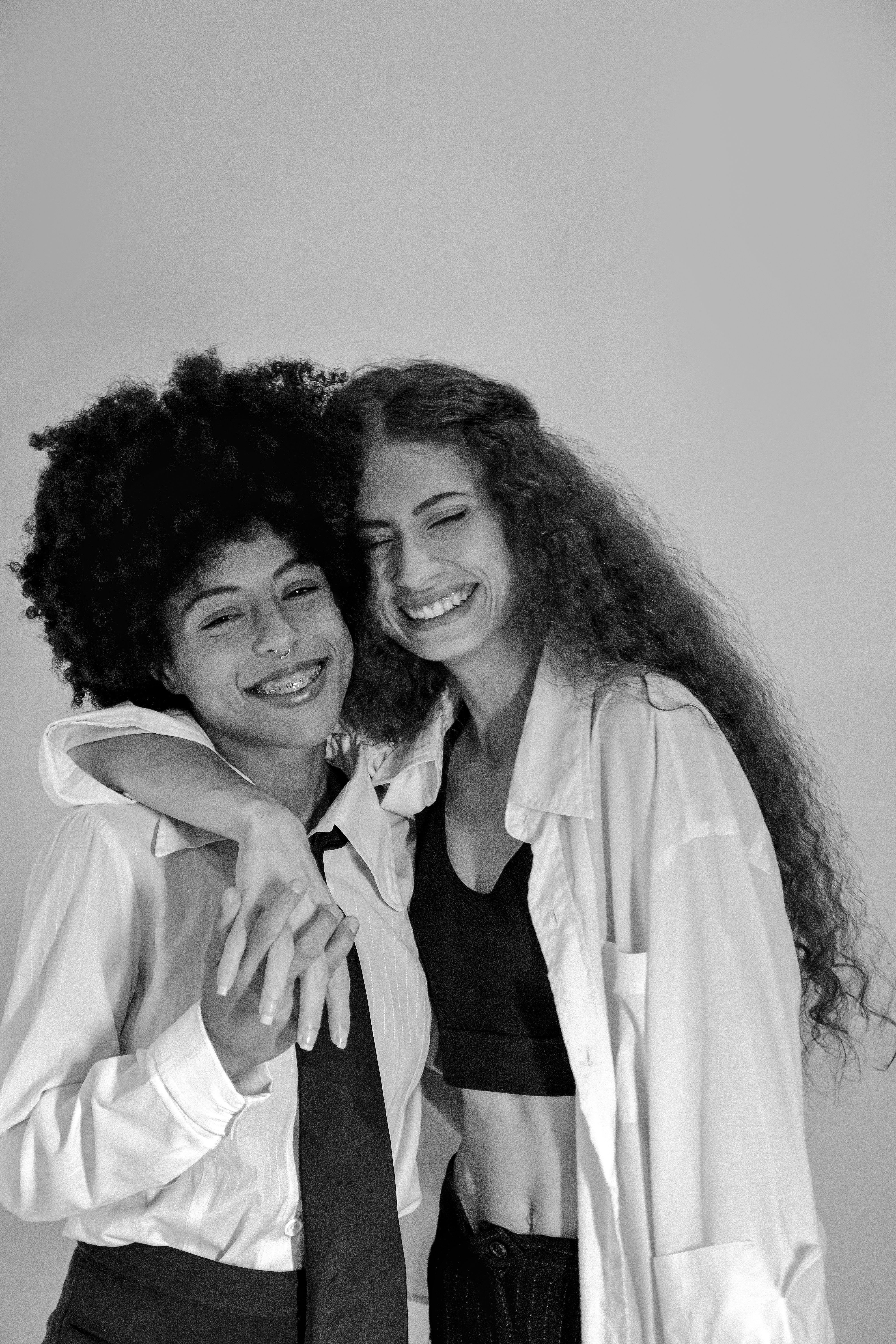 Bright and cheerful black and white photo of two women embracing in a studio setting.