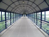 一座有盖的宽人行天桥，在现代城市环境中融入了几何设计元素