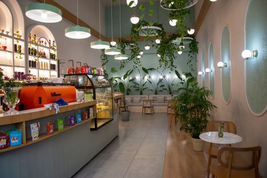 Contemporary café interior featuring lush greenery, modern lights, and a cozy seating area.