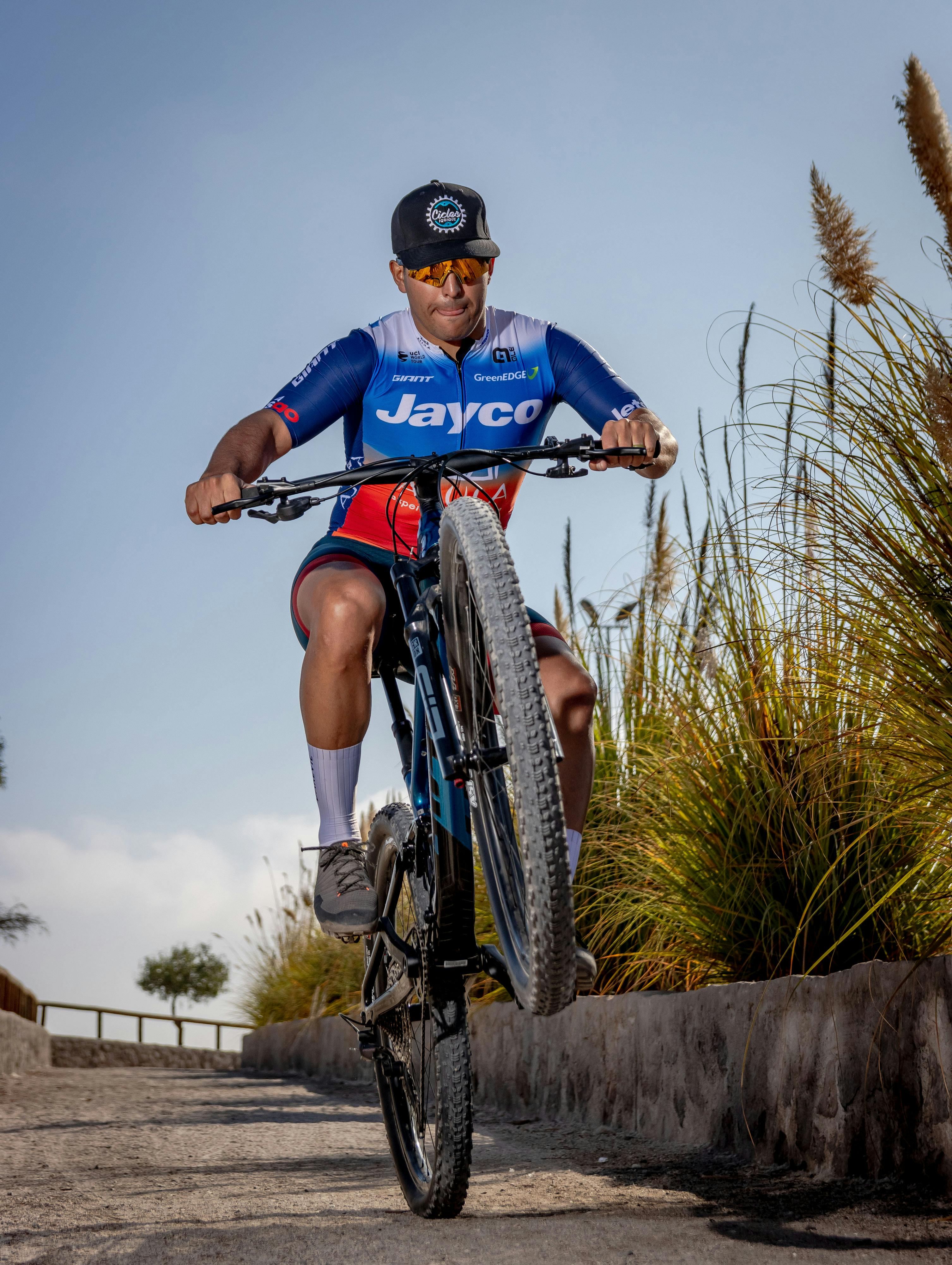 Mountain biker in sports gear performs a wheelie on a rural path in Alto Hospicio, Chile.