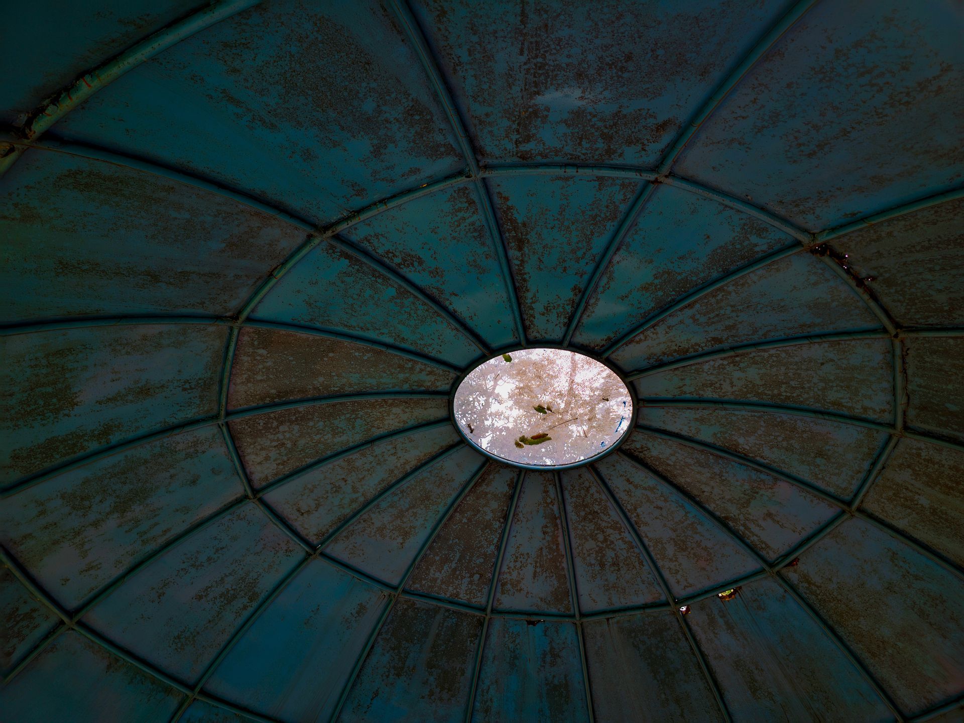 View of a rusty circular metal structure's ceiling with a central skylight in Dhaka, Bangladesh.