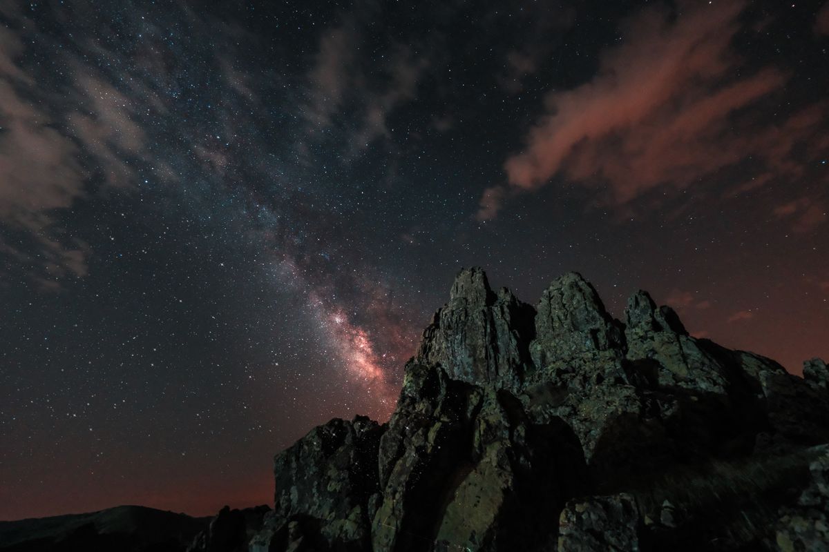 A breathtaking view of the Milky Way over sharp mountain peaks under a vibrant starry night sky.