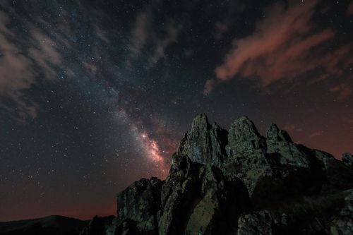 Free A breathtaking view of the Milky Way over sharp mountain peaks under a vibrant starry night sky. Stock Photo