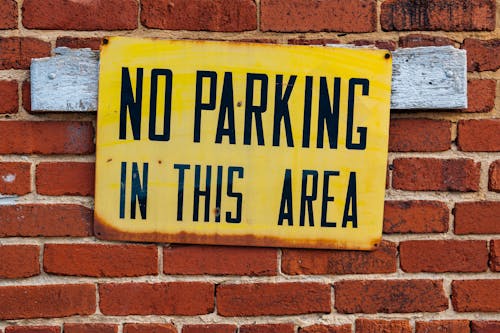  A no parking sign on a brick wall 
