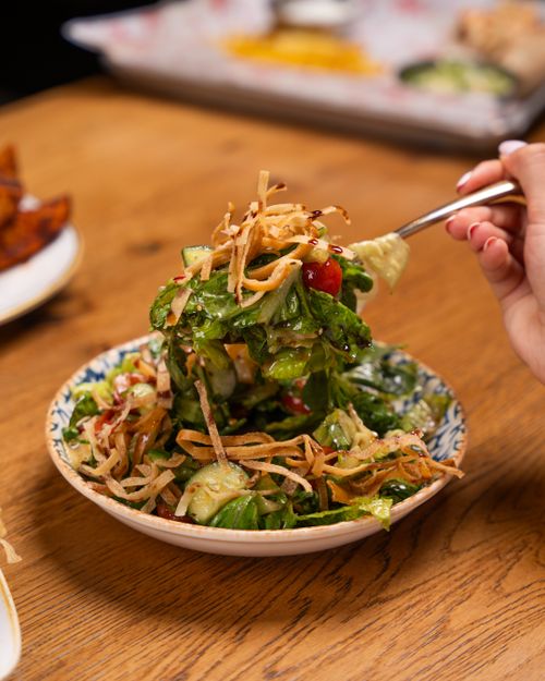 Free Close-up of a fresh mixed salad with crispy toppings on a wooden table. Stock Photo