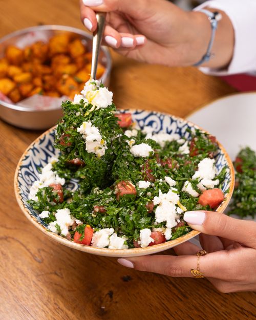 Free Close-up of a colorful tabbouleh salad with feta cheese in a patterned bowl held by a woman. Stock Photo