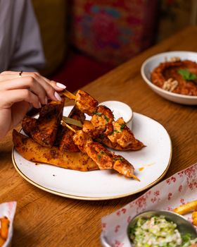 Close-up of gourmet chicken skewers and potato wedges served on a plate.