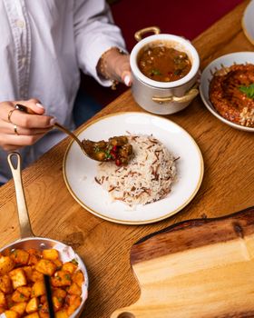 Close-up of a diverse meal setting with rice, curry, and potatoes served on a wooden table.