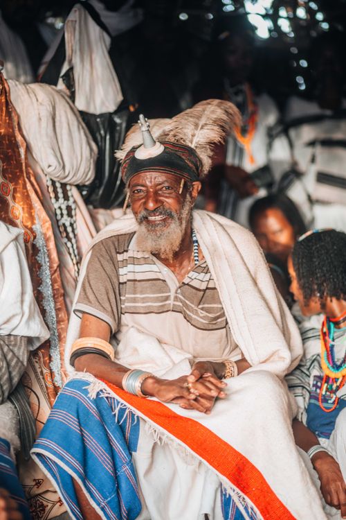 Free Portrait of an elderly man wearing traditional tribal clothing, sitting and smiling warmly. Stock Photo
