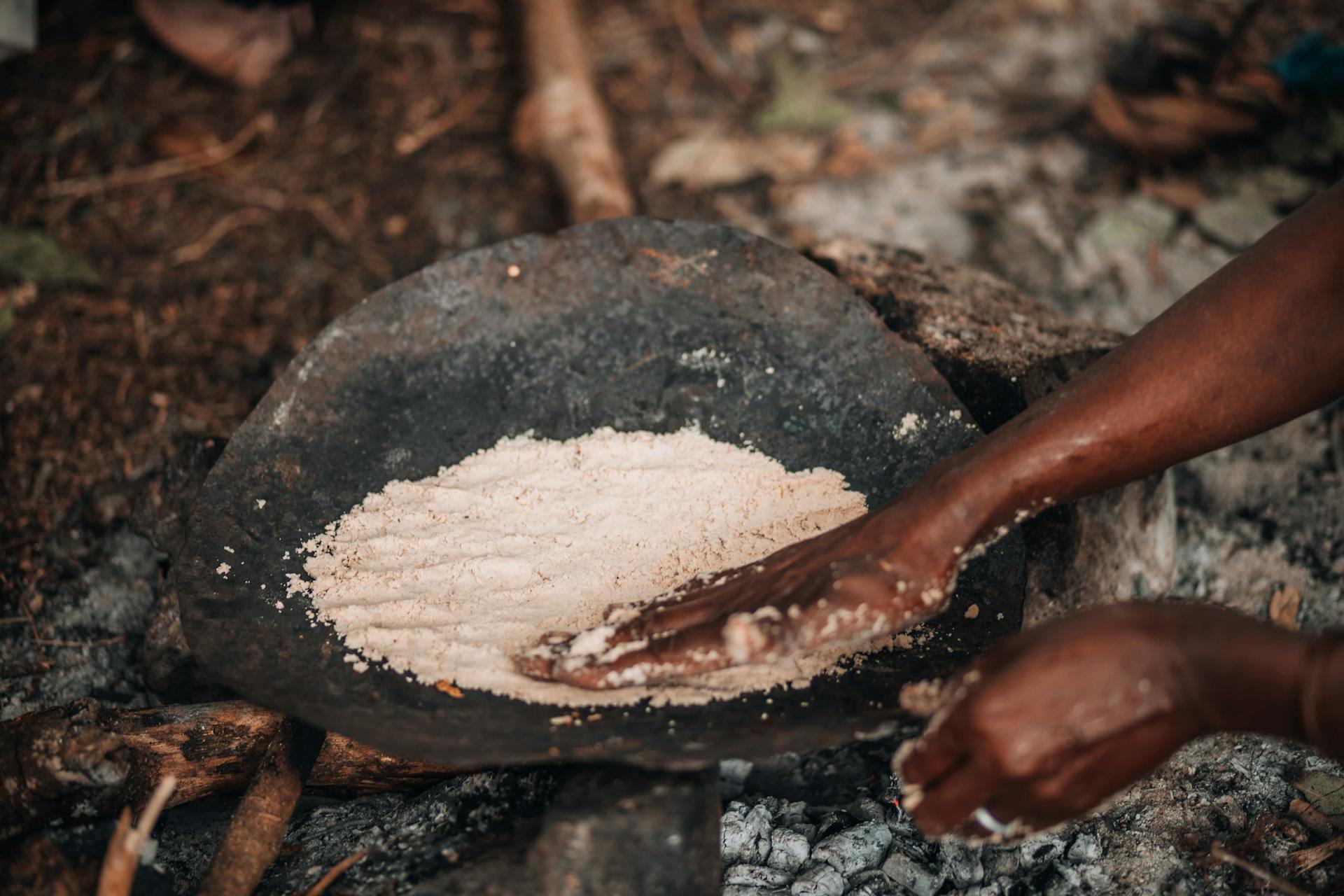 Hands of Person Working with Powder on Tray on Ground