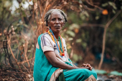 An old woman sitting in the woods with a basket