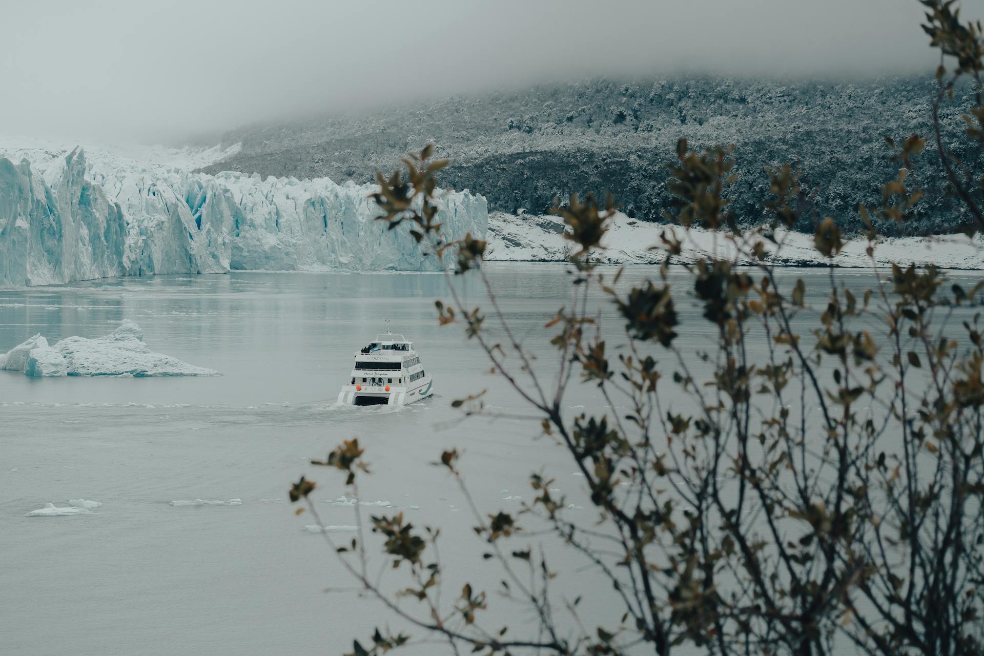 A scenic winter cruise ship navigating through icebergs near a glacier coastline.