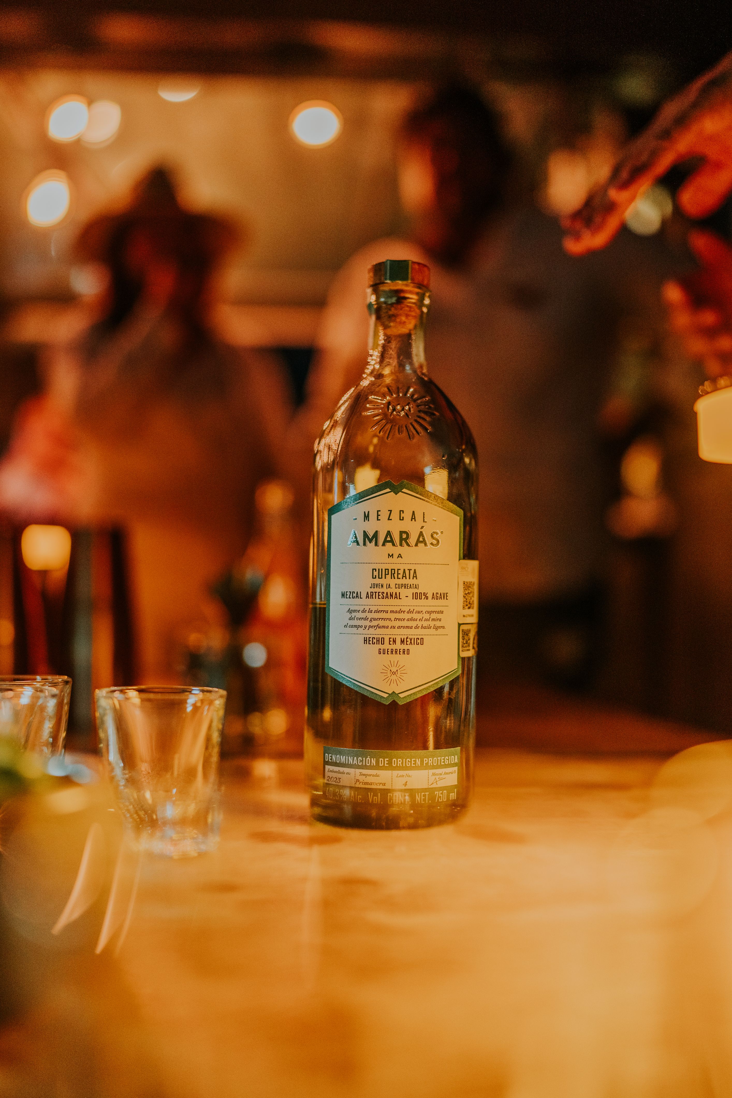 Mezcal Amaras bottle prominently displayed in a bar with blurred background.