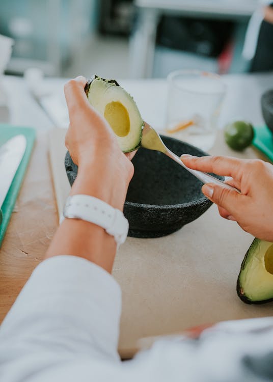 A woman is cutting an avocado with a knife