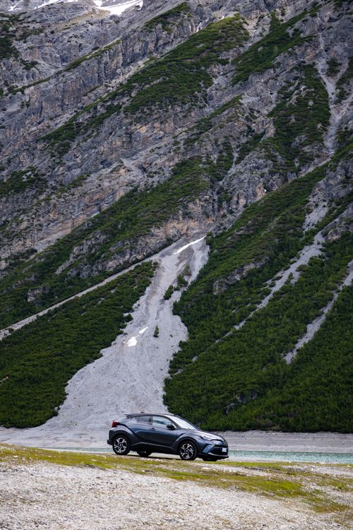 Free A sleek car parked on a steep, scenic mountain road in Livigno, Italy with lush greenery and rocky terrain. Stock Photo