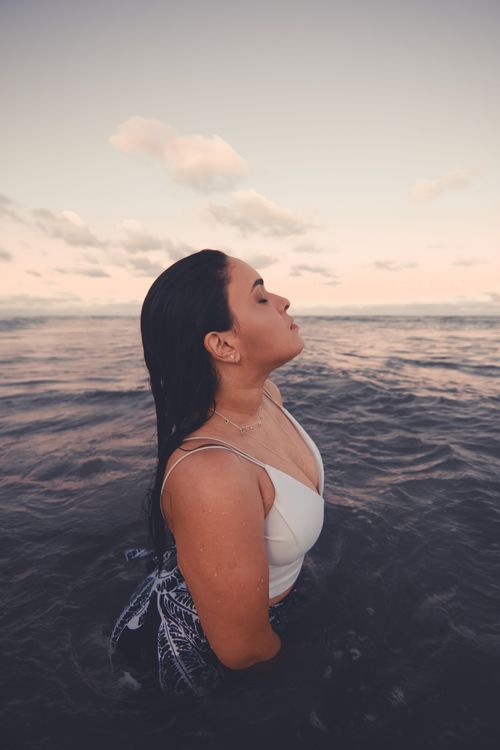 Free A peaceful portrait of a woman standing in the ocean at sunset, exuding tranquility. Stock Photo