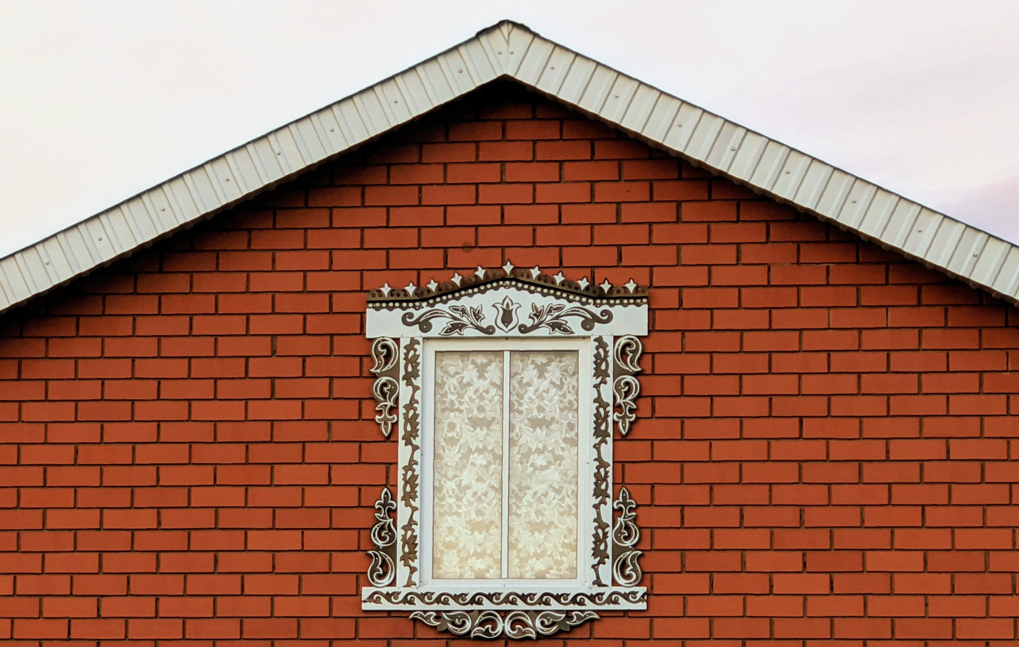 Red brick facade featuring ornate window frame and decorative elements.